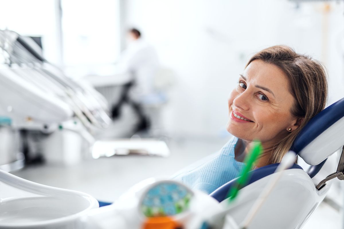 Is Periodontitis Serious Female dentist smiling at dental chair in modern office clinic setting